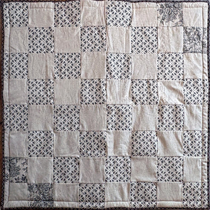Patchwork picnic blanket with geometric patterns in neutral shades of beige & brown