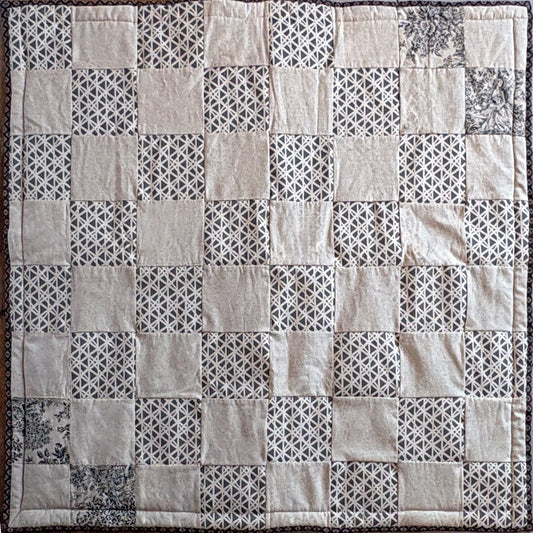 Patchwork picnic blanket with geometric patterns in neutral shades of beige & brown