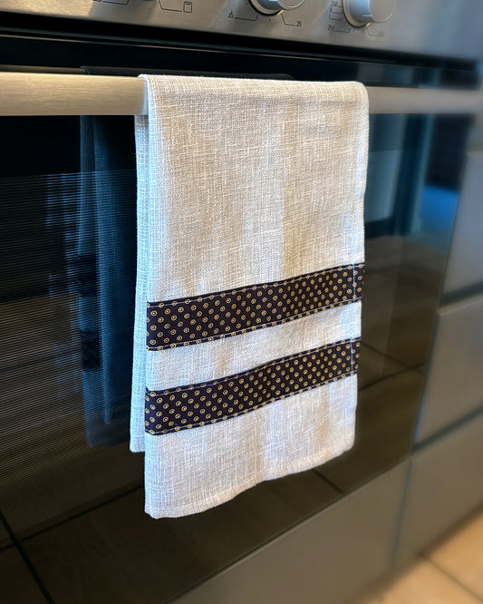 Beige Tea Towel with Brown Dots Shwe Shwe fabric accents, hanging in front of oven door.