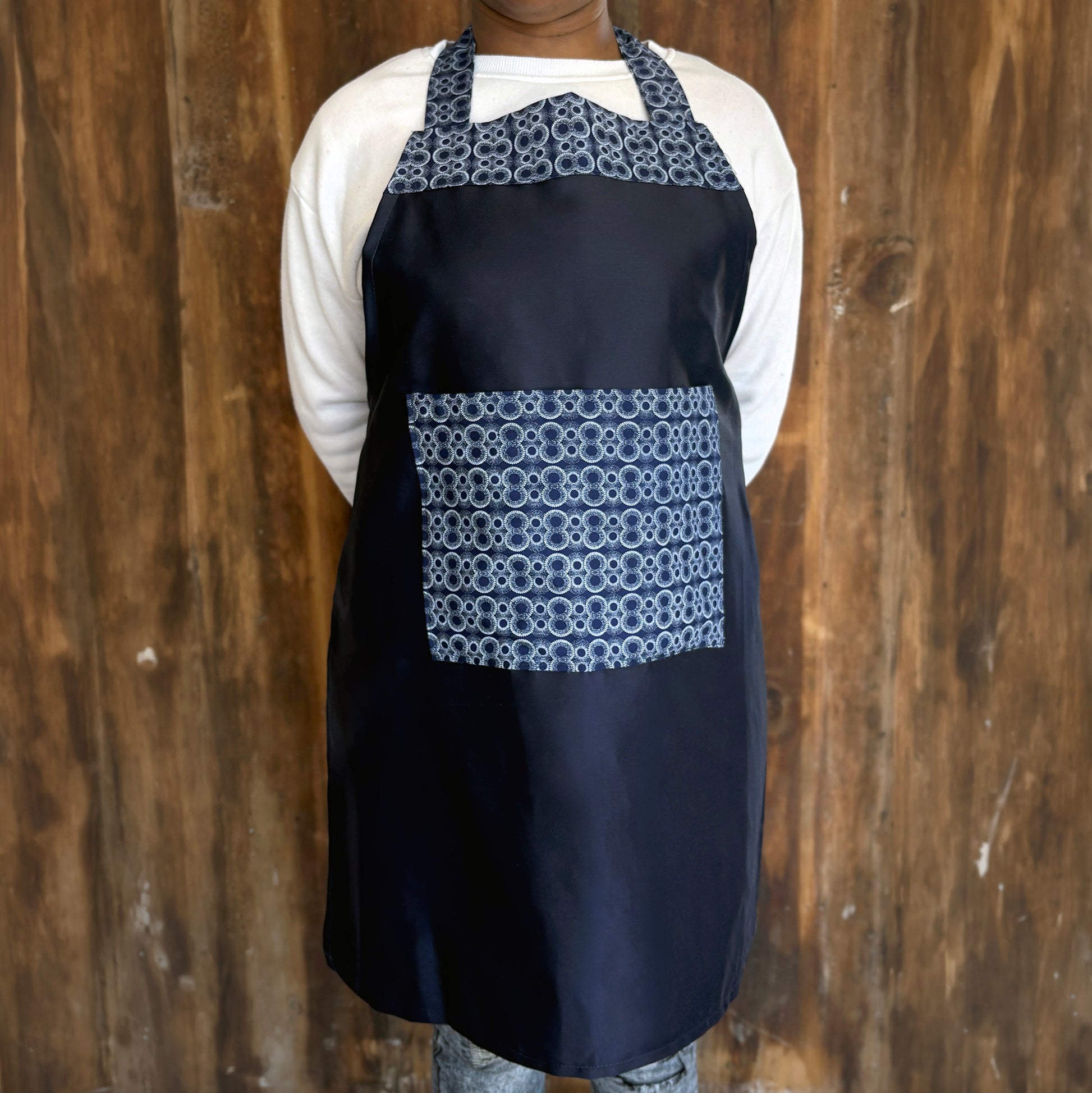 Person wearing a blue apron with patterned Shwe Shwe pocket and top accent.