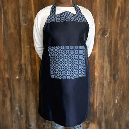 Person wearing a blue apron with patterned Shwe Shwe pocket and top accent.