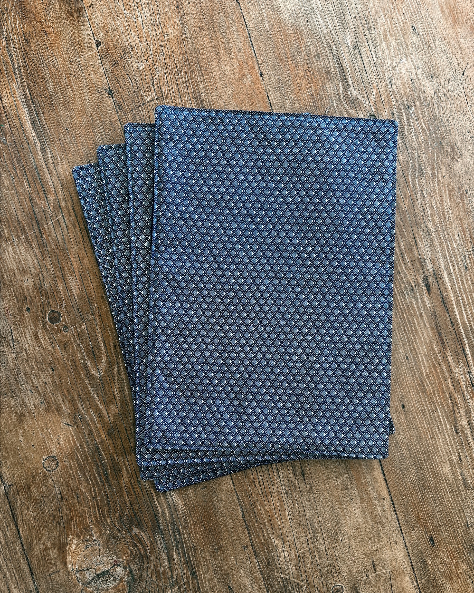 Blue ShweShwe Fabric placemats with White Diamond print on wooden table.