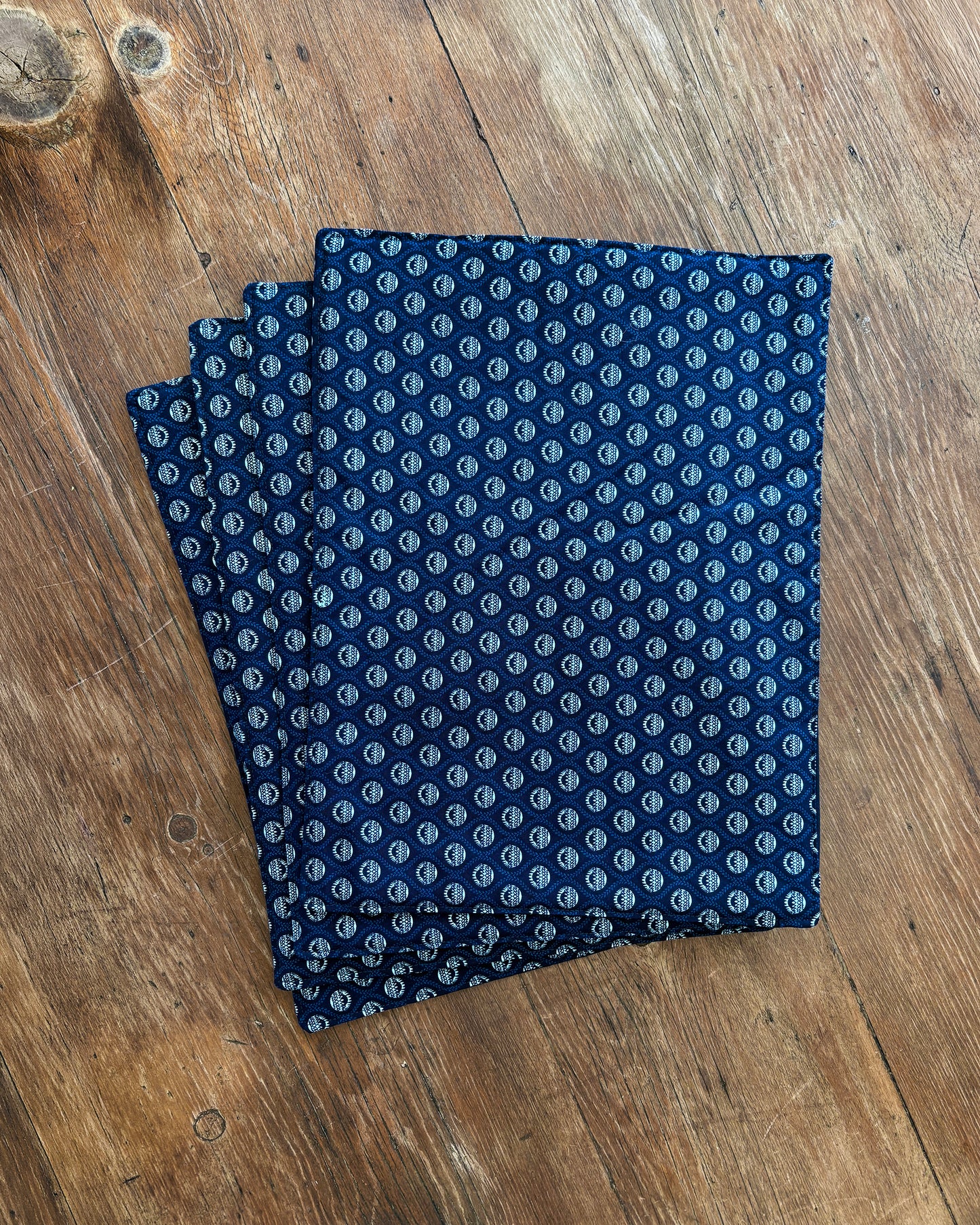 Blue ShweShwe Fabric placemats with White Protea print on wooden table.