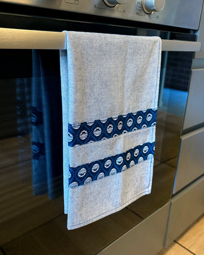Blue Tea Towel with Protea Shwe Shwe fabric accents, hanging in front of oven door.
