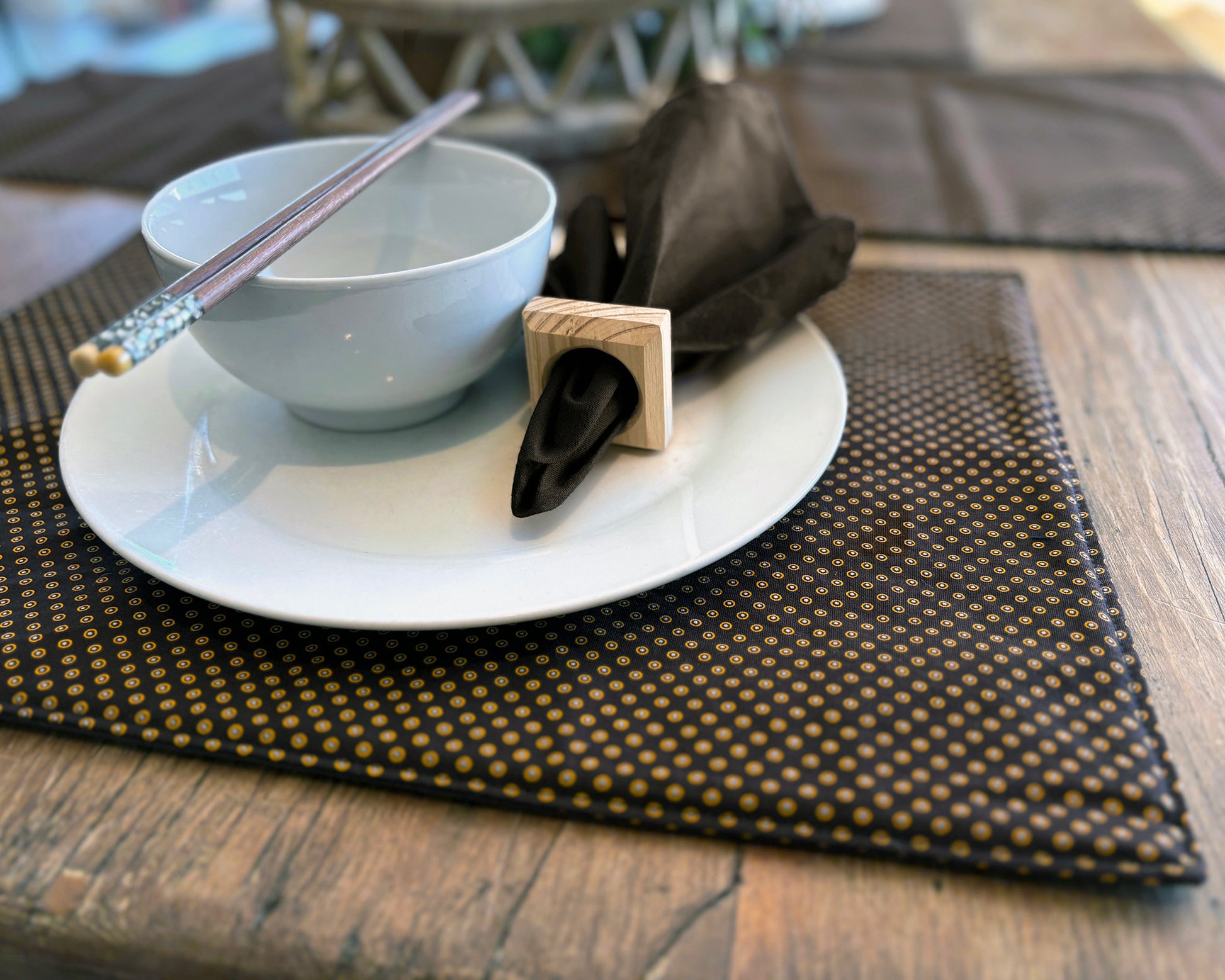 Close up of Brown Shwe Shwe Fabric placemats with White & Yellow Dots print on wooden table.