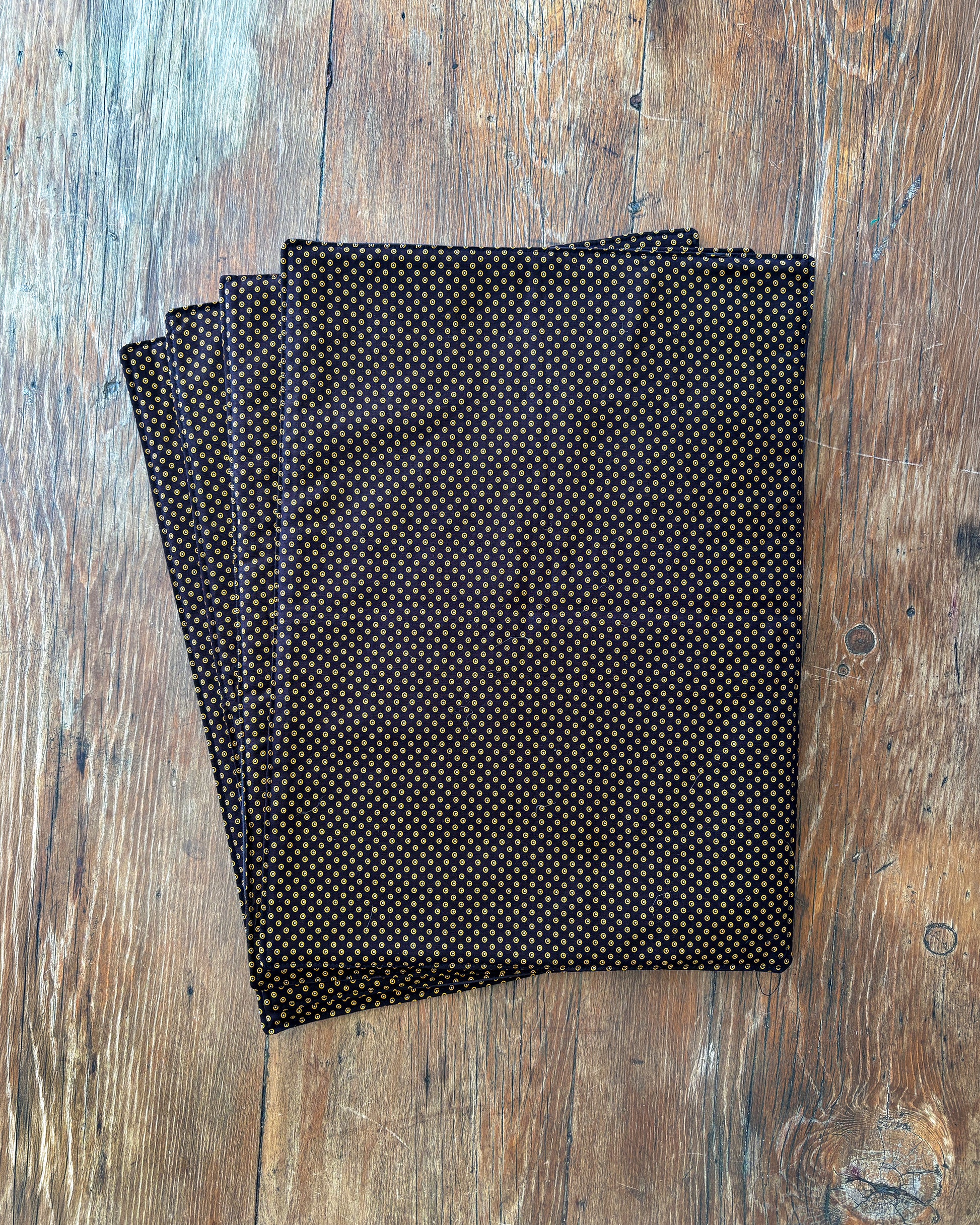 Brown Shwe Shwe Fabric placemats with White & Yellow Dots print on wooden table.