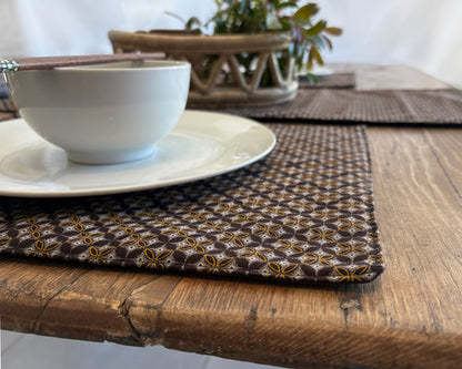 Close up of Brown Shwe Shwe Fabric placemats with White & Yellow Geometric print on wooden table.