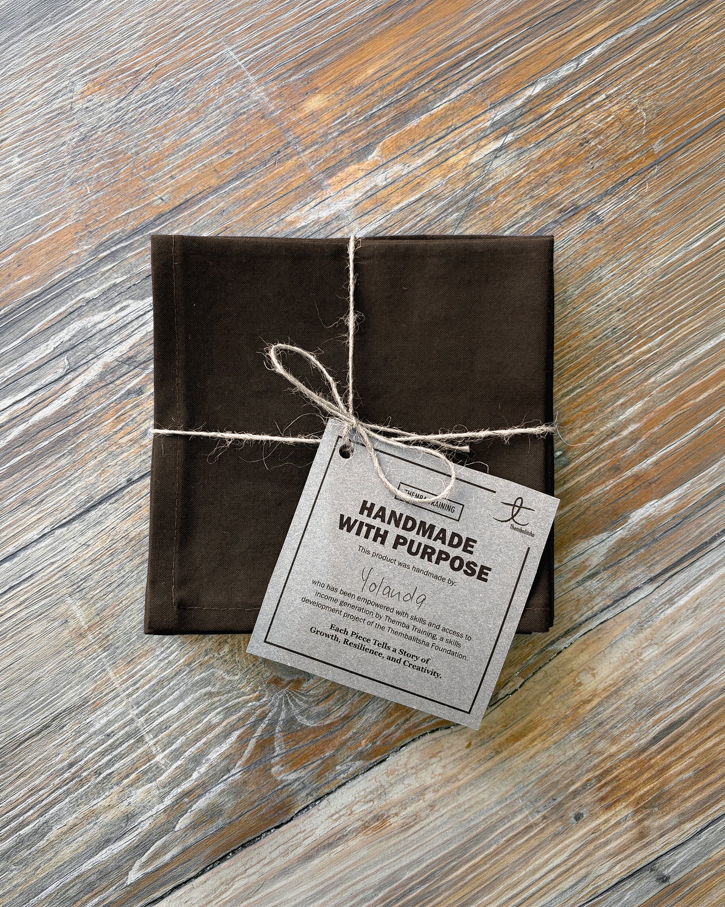 Brown fabric napkin set of 4 on a wooden surface.