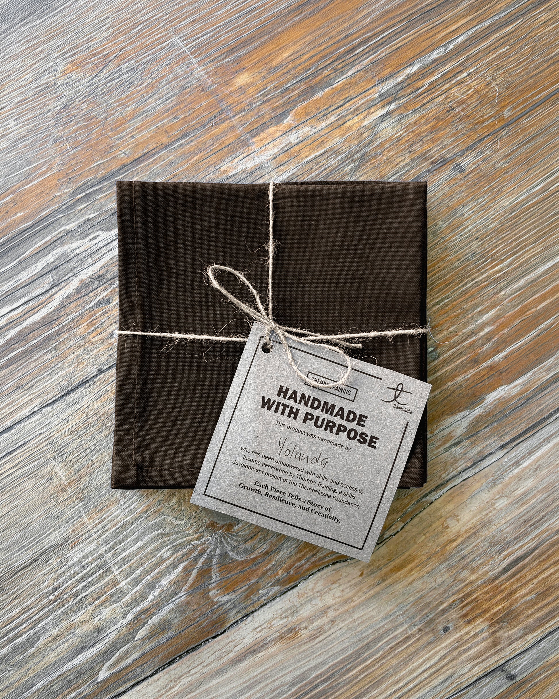 Brown fabric napkin set of 4 on a wooden surface.