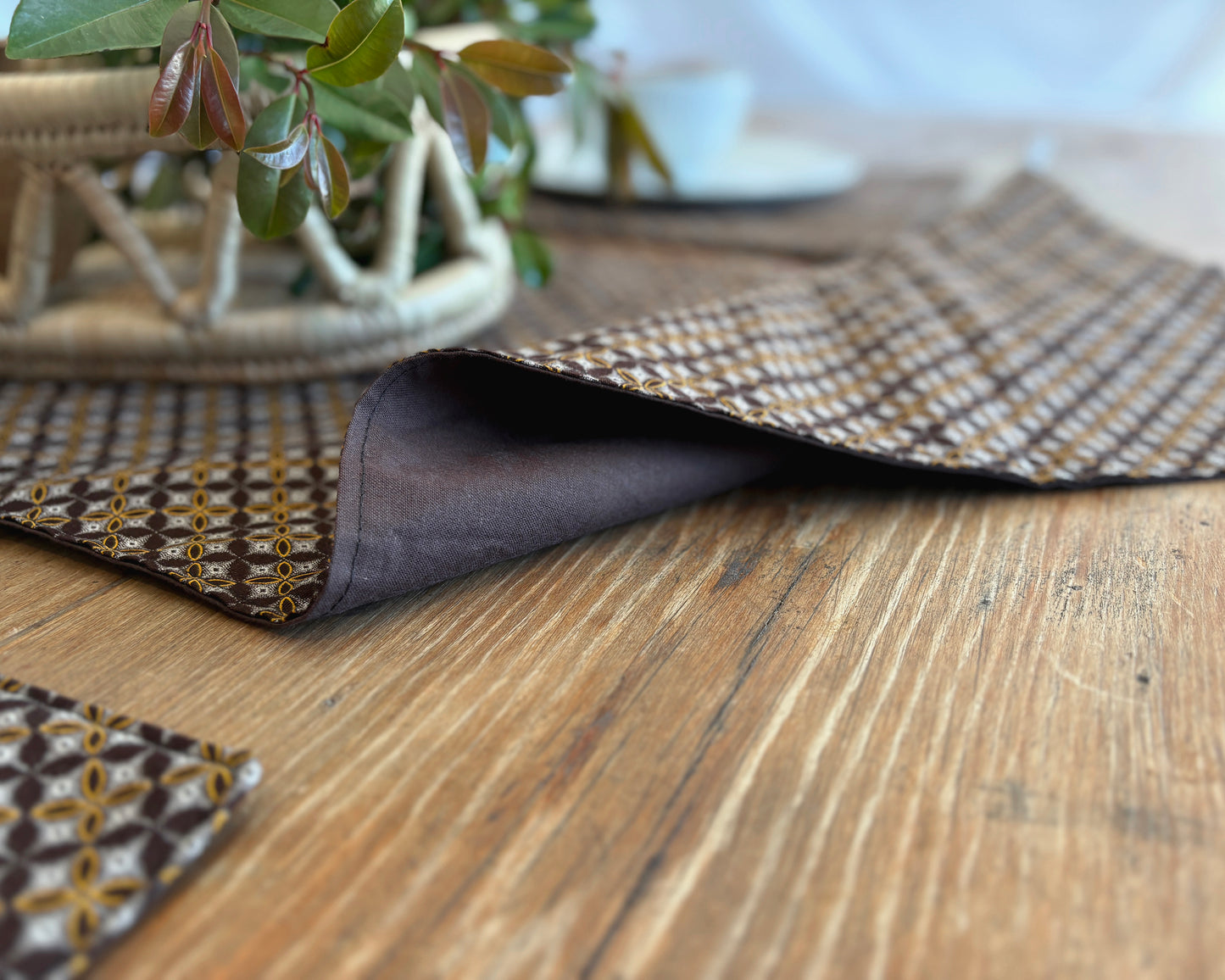 Brown Shwe Shwe lined fabric Table runner on wooden table. Geometric Yellow & white traditional print on brown fabric.