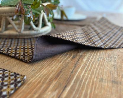 Brown Shwe Shwe lined fabric Table runner on wooden table. Geometric Yellow & white traditional print on brown fabric.