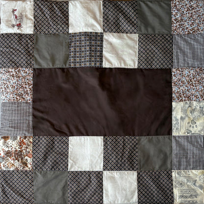 Patchwork picnic blanket with various patterned  brown fabric squares around a plain brown middle inset.