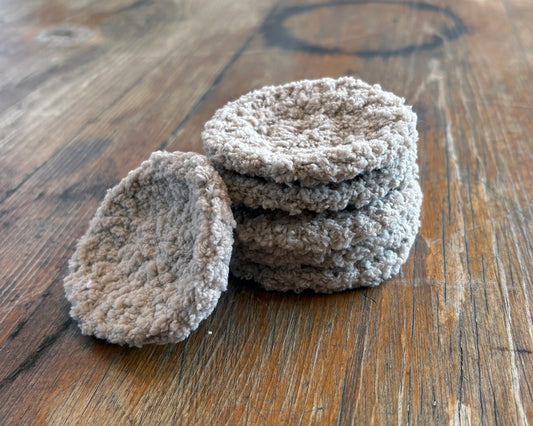 Stack of reusable round crochet face scrubbies on a wooden surface