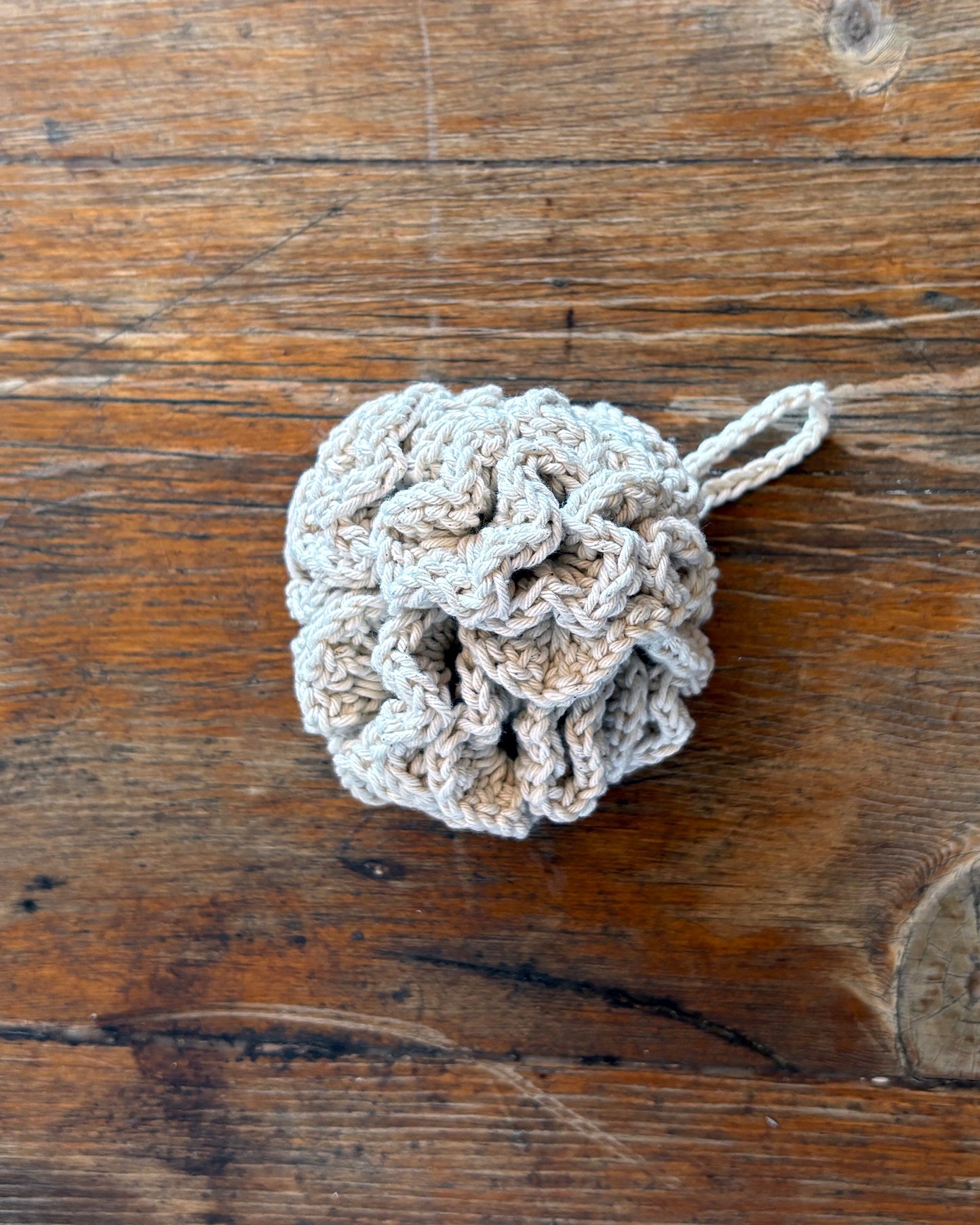 Natural White Crocheted loofah on a wooden surface