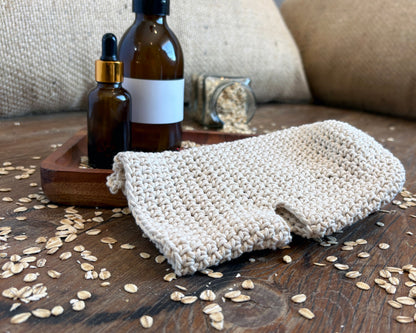 Lifestyle photo of a natural white crochet wash glove on a wooden surface