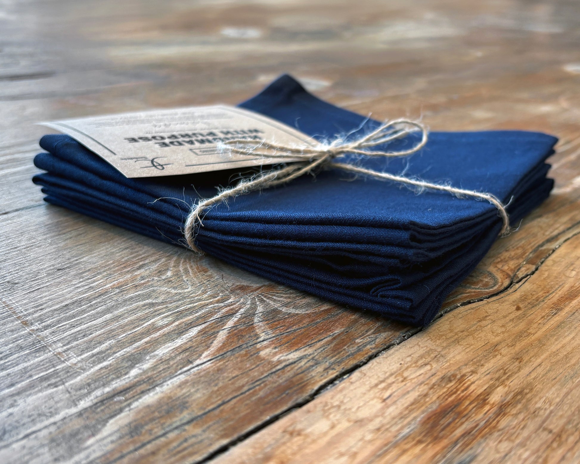 Set of 4 navy blue napkins on a wooden surface. Side view.