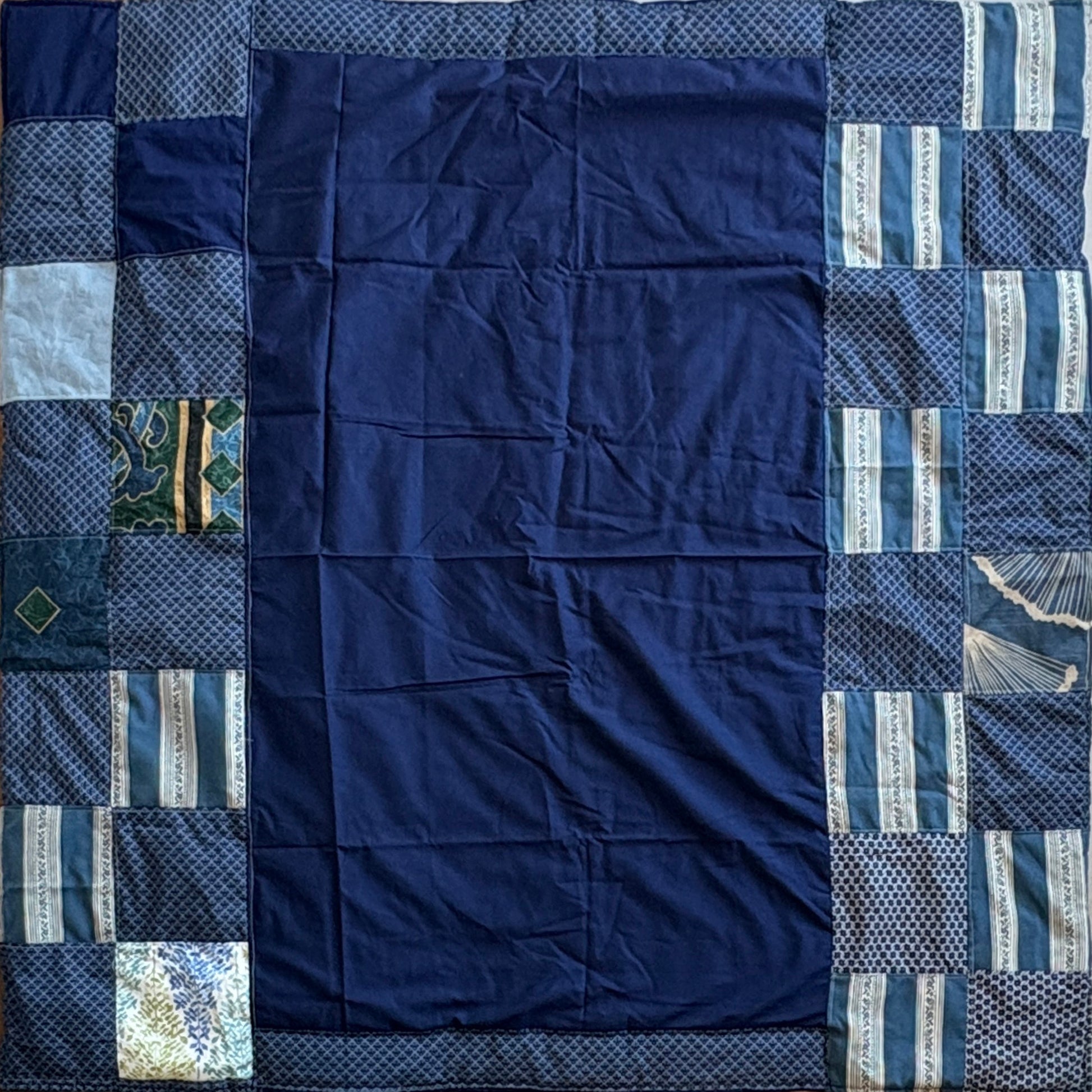 Navy blue patchwork picnic blanket with various blue blocks around blue middle patch