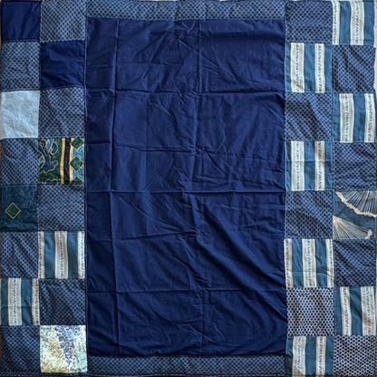 Navy blue patchwork picnic blanket with various blue blocks around blue middle patch