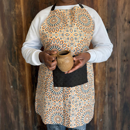 Person wearing an orange & brown geometric patterned Shwe Shwe apron with brown front pocket