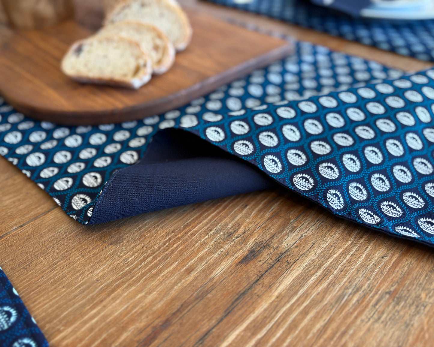 Navy Shwe Shwe lined fabric Table runner on wooden table. Protea print on fabric.
