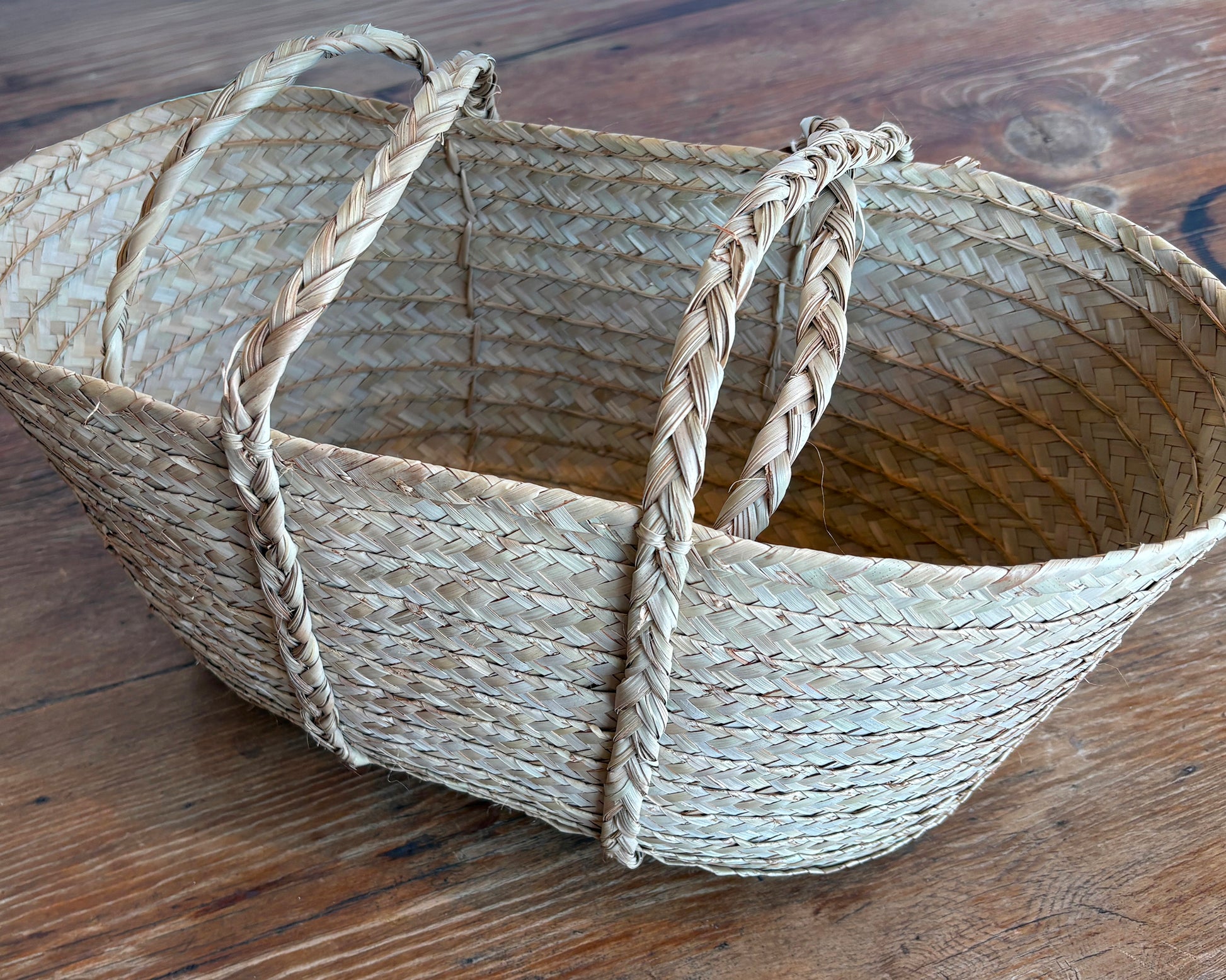 Woven picnic basket with handles on a wooden surface